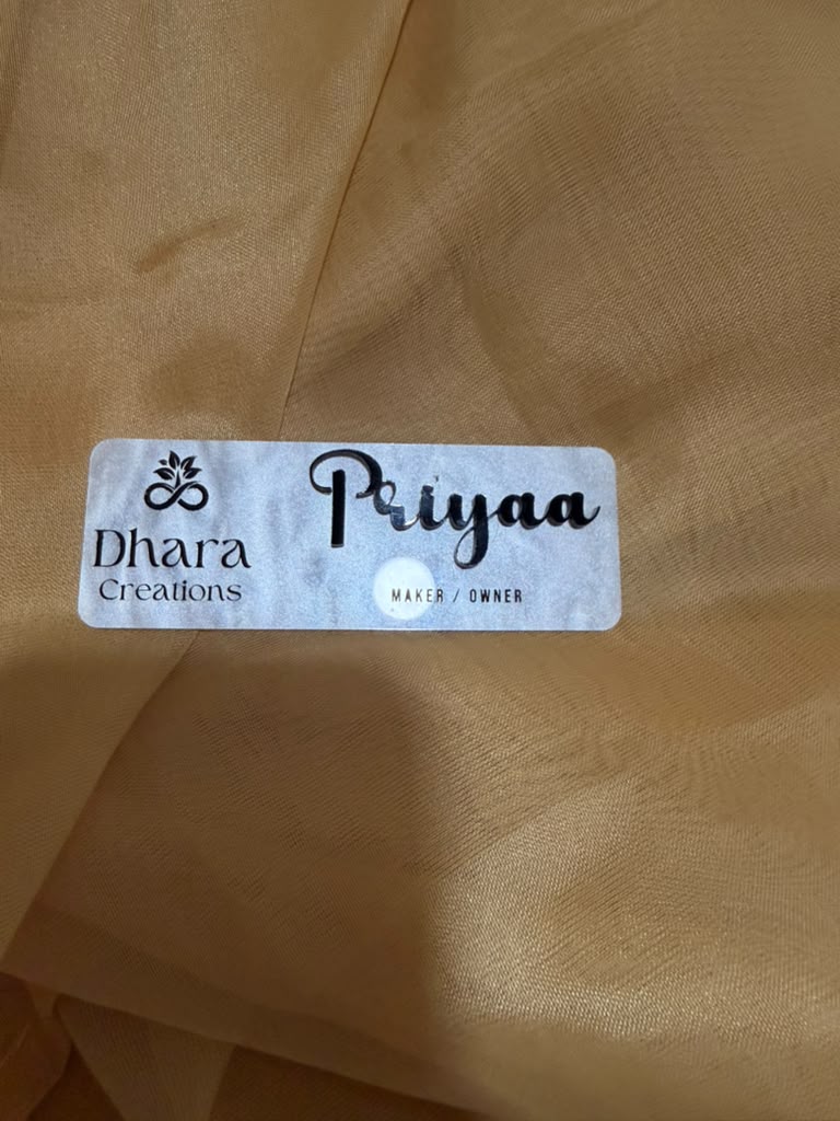 Marble acrylic name badge with Dhara Creations logo and Priyaa Maker Owner engraved